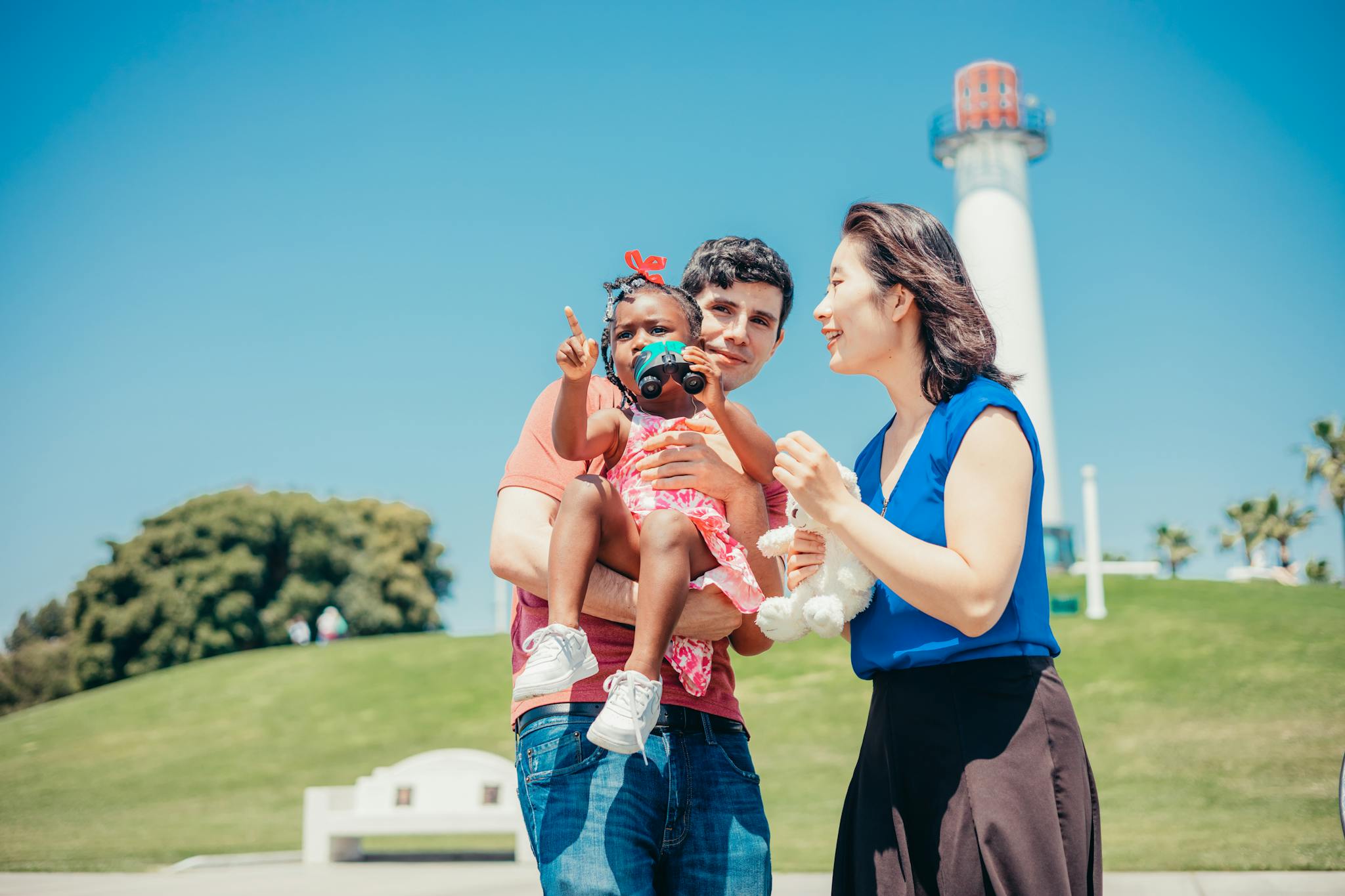 Happy multicultural family enjoying a sunny day in the park with a baby girl.