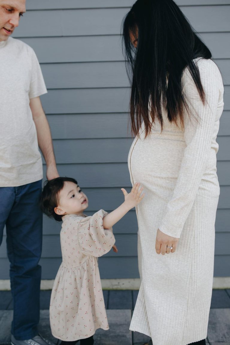 A family moment with a child touching a pregnant mother's tummy, embracing togetherness.