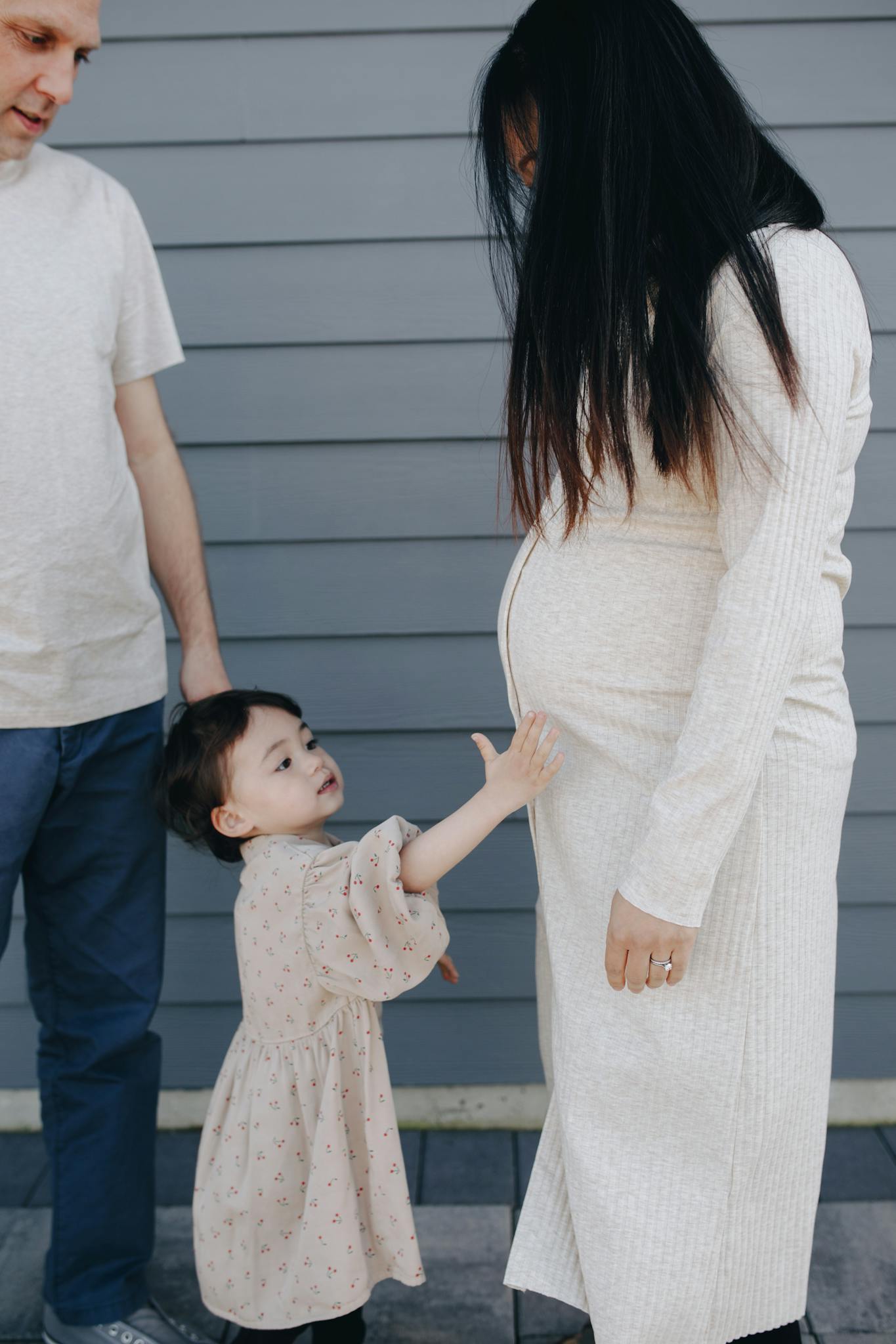 A family moment with a child touching a pregnant mother's tummy, embracing togetherness.