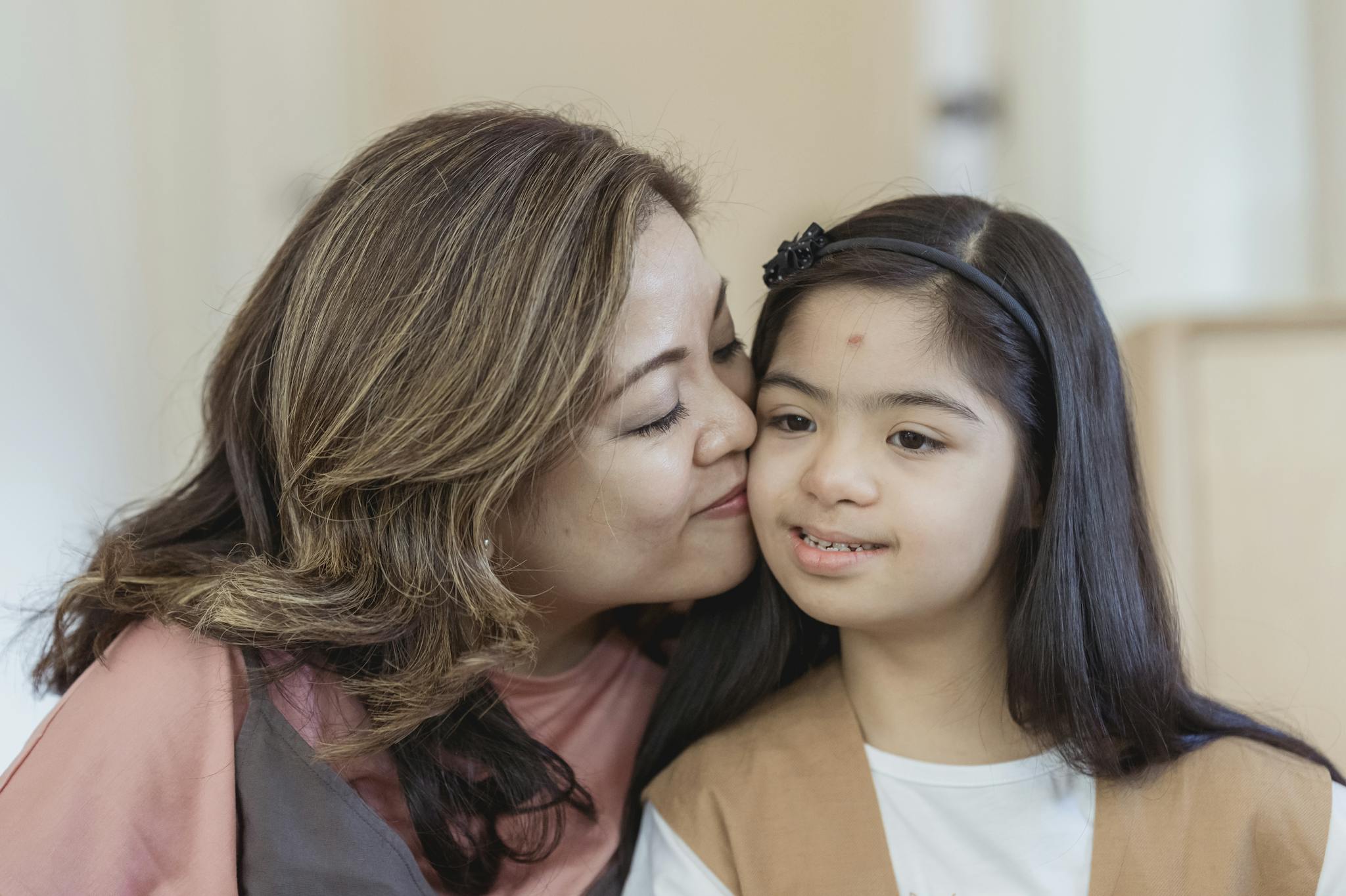 Heartwarming moment of a mother lovingly kissing her daughter with Down syndrome.