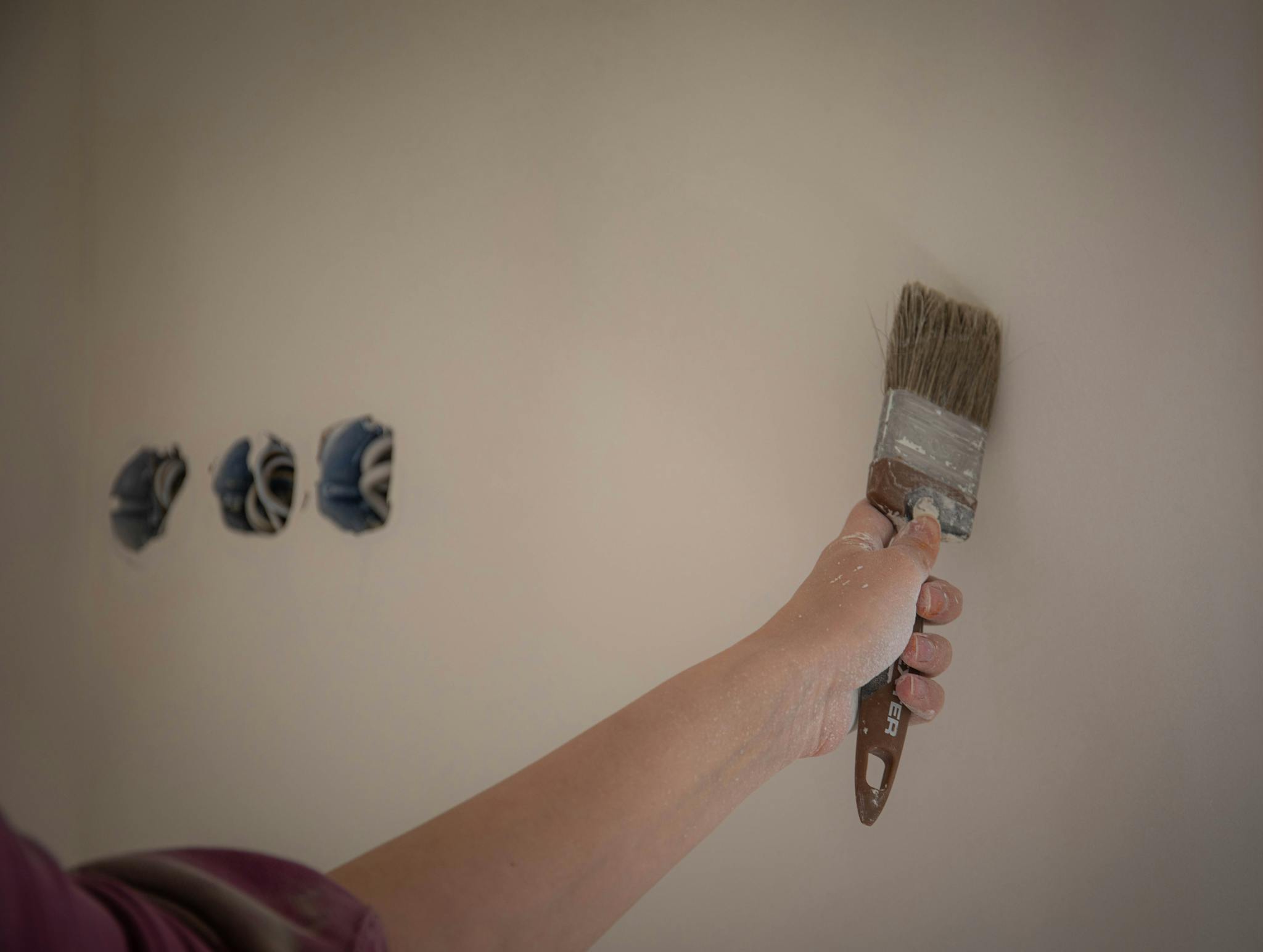 A person painting a wall with a brush, showcasing a home makeover process.